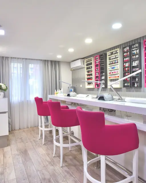Nail bar u salonu Enigma: stolice u boji fuksije i zid pun lakova